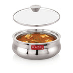 Casserole filled with paneer curry with its glass lid detached and floating above it, on a white background.