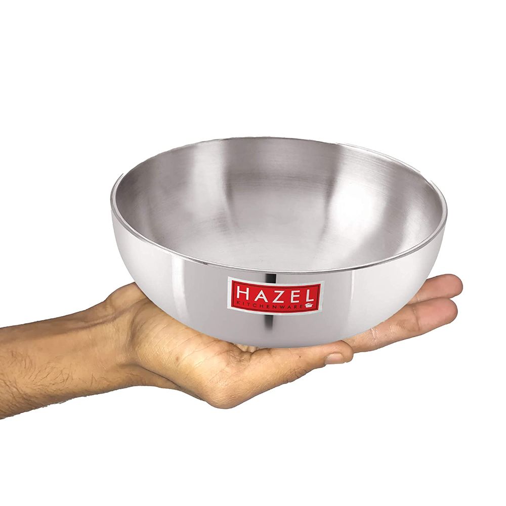Empty aluminium tasla balanced on an open palm to show its size, against a white background.