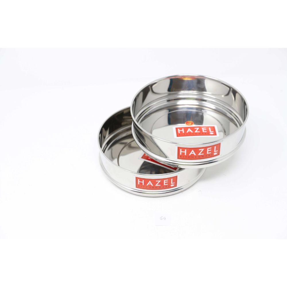Two empty stainless steel flat dabbas stacked together at an angle, shown on a plain white background.
