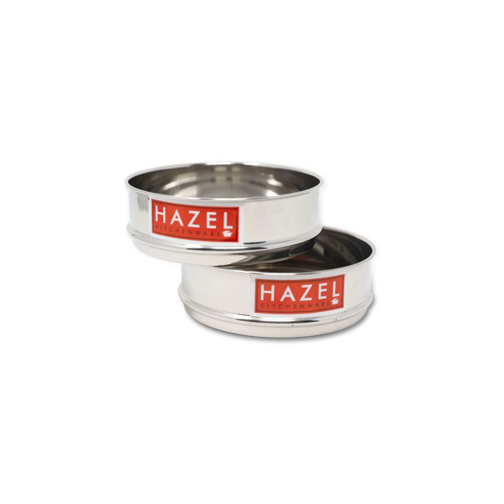 Two empty stainless steel flat dabbas placed side by side, shown from a low front angle on a plain white background.