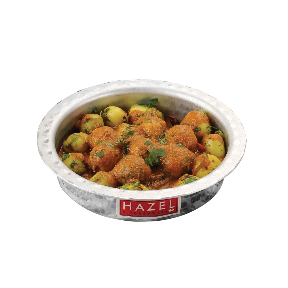 Bhagona filled with potato curry, lid removed, shown on a plain white background.