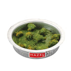 Close front view of the hammered aluminium dekchi filled with green curry, without the lid, on a white background.