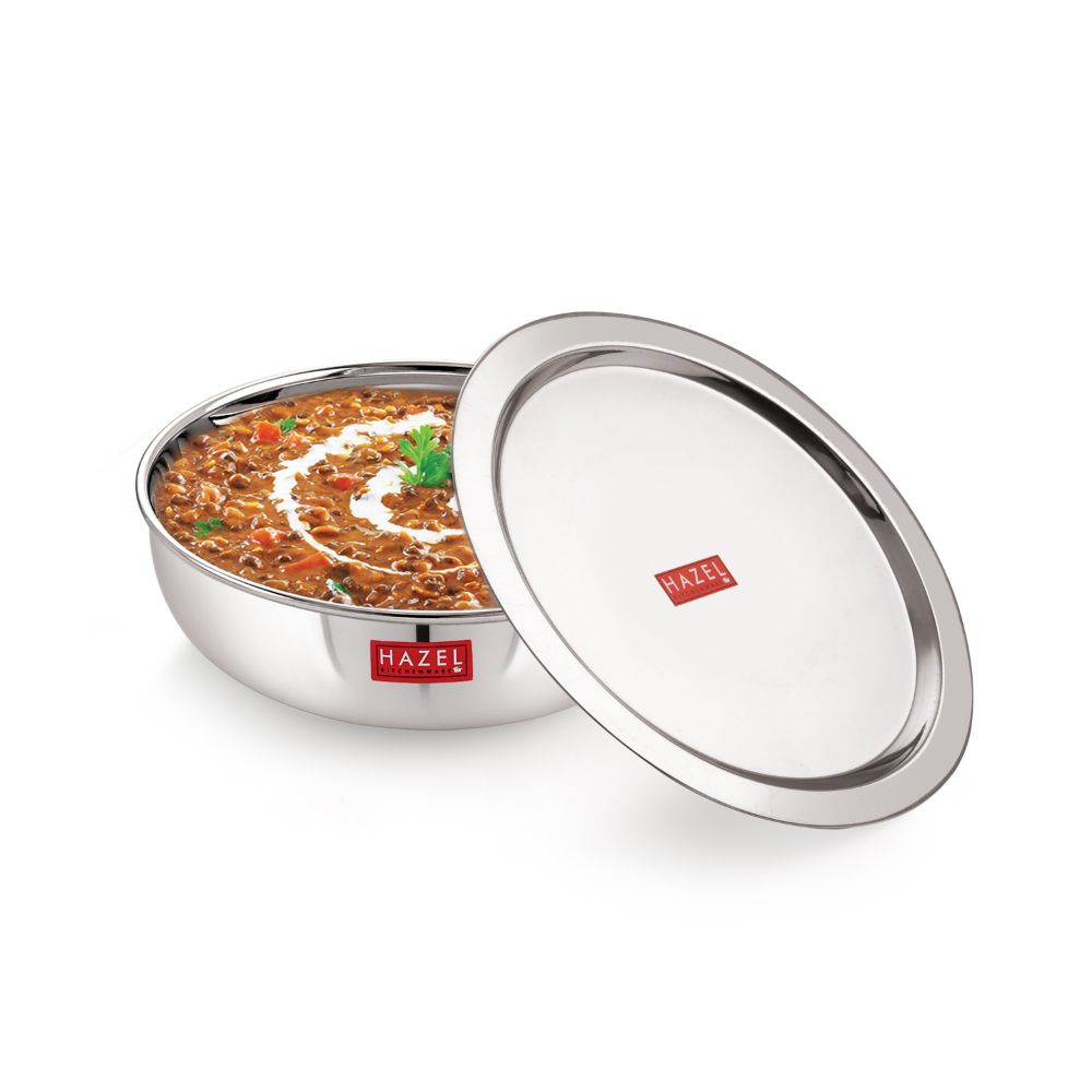 Stainless steel tasla and kadai with lid containing a prepared dish.