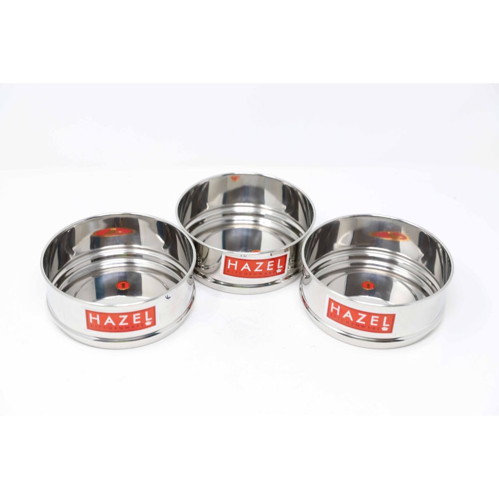 Three empty steel cooker dabbas grouped closely together on a plain white background.