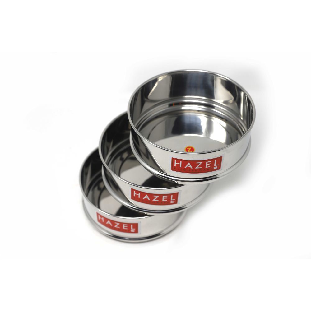 Three stainless steel dabbas fanned out diagonally in a cascading arrangement, showing their open interiors