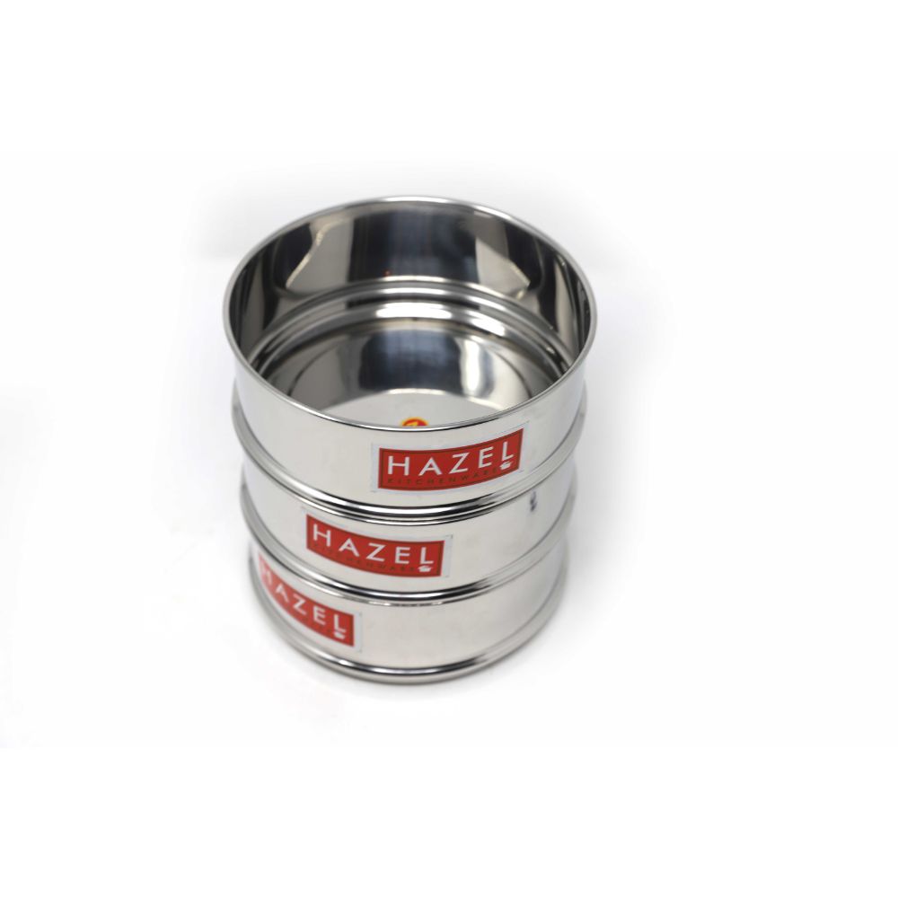 Three empty stainless steel cooker dabbas stacked vertically, each with a HAZEL brand label