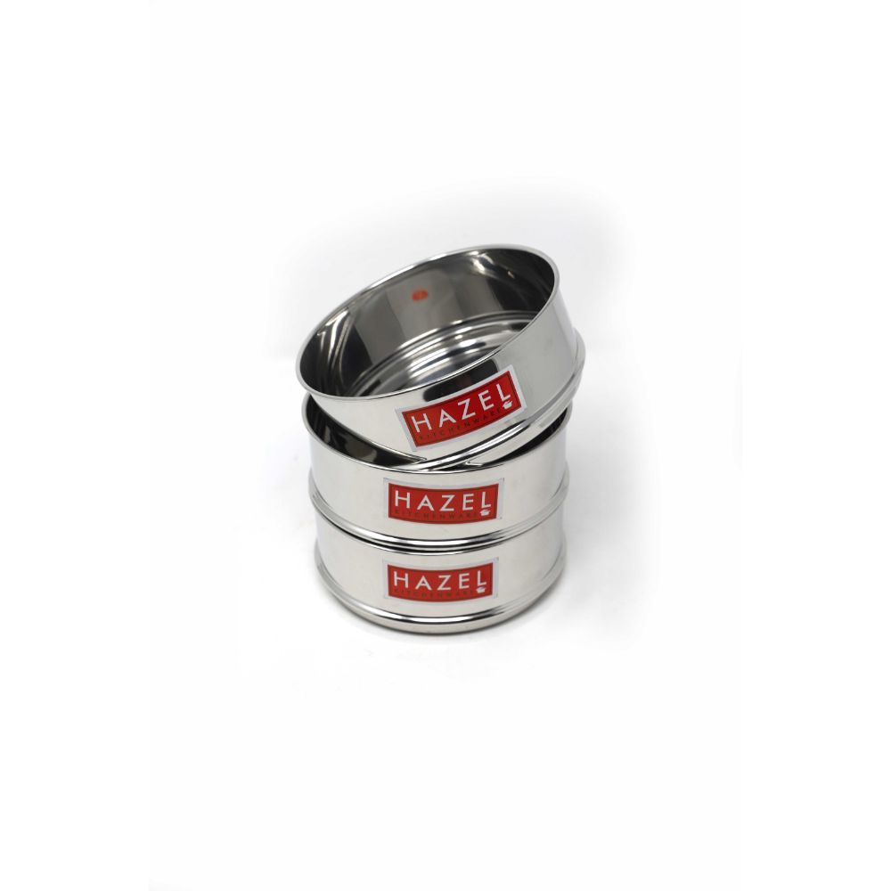 Three stainless steel dabbas stacked and tilted at an angle, showing the open top of the uppermost dabba