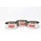 Three empty stainless steel cooker dabbas placed upright side by side, each with a HAZEL brand label