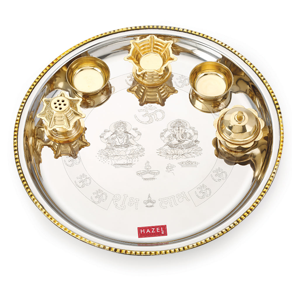 Empty stainless steel pooja thali set with brass diya, vatis, and incense holder arranged on the engraved plate