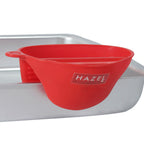 A red silicone mitt gripping the edge of a metal baking tray.