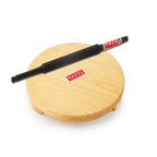 Wooden chakla board with the black belan resting on top against a white background.