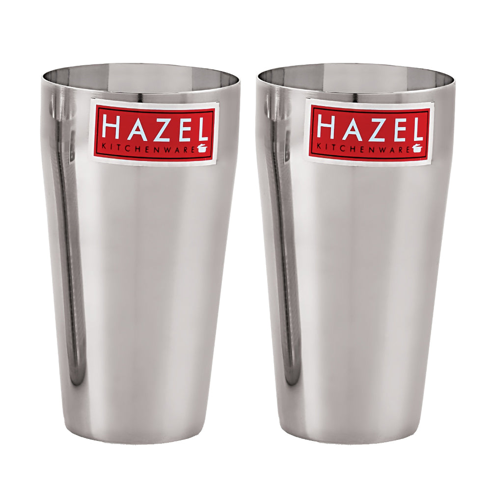 Two empty stainless steel jumbo lassi glasses standing side by side on a plain white background.