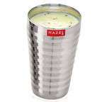 A single steel glass filled with lassi topped with garnish, shown on a white background.