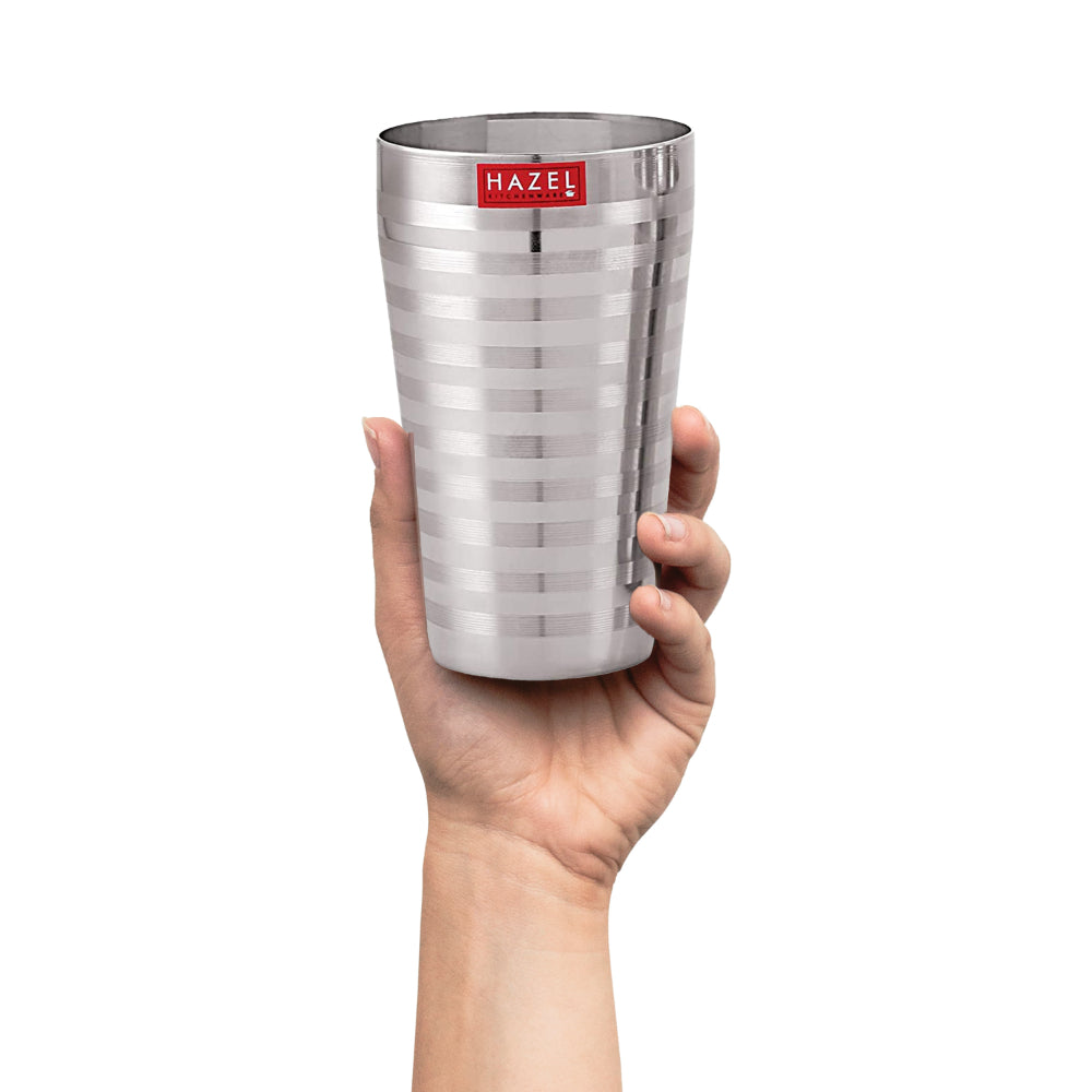 A hand holding a single steel jumbo glass to show scale.