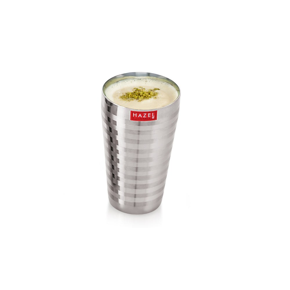 A small single steel glass filled with lassi shown at reduced scale on a white background.