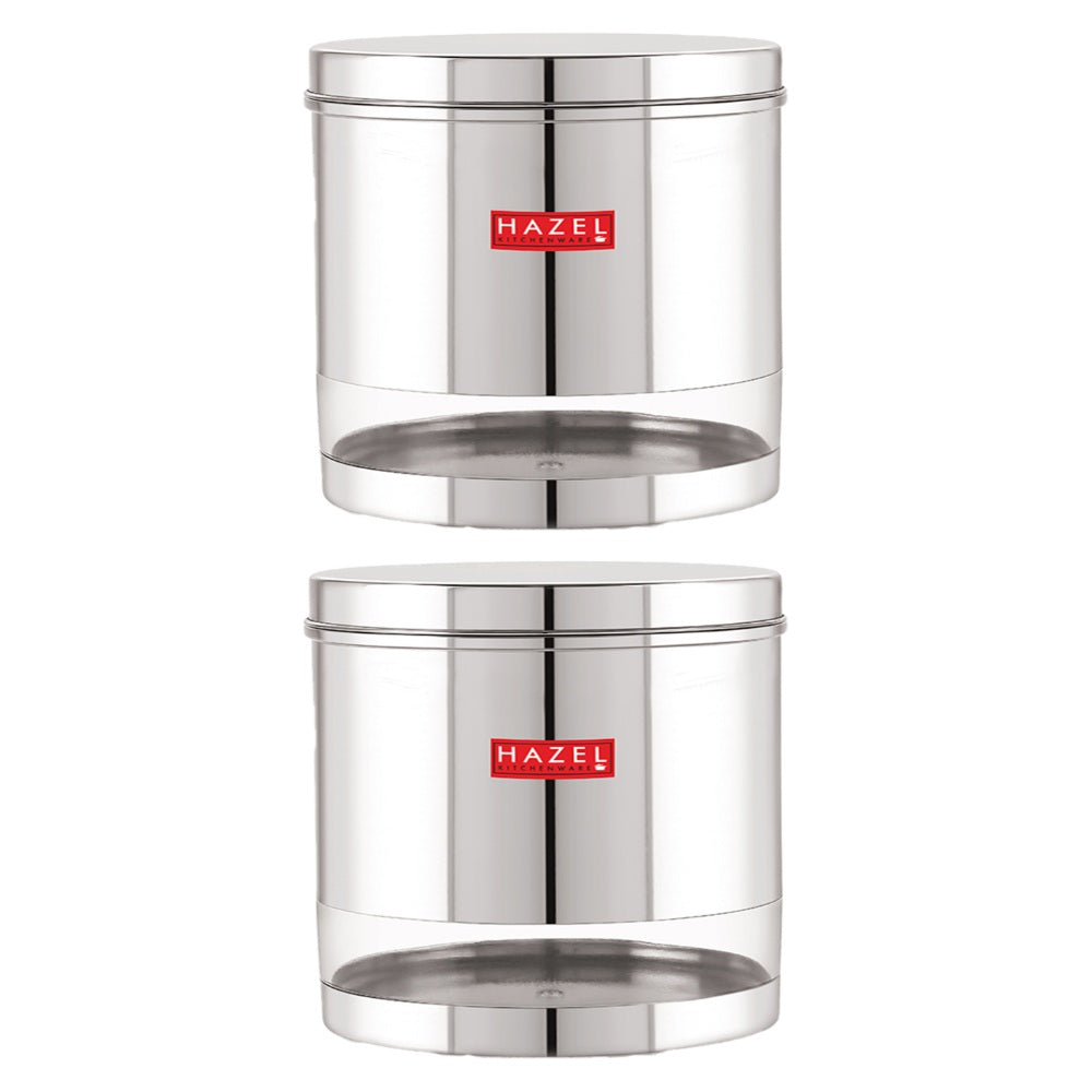 Set of two transparent steel storage dabbas with steel lids stacked on a plain white background.
