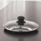 Clean studio shot of the tempered glass lid with black knob and steel rim on a plain white background.