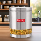 Container filled with sprouted grains standing on a wooden kitchen counter with shelves and a sink in the background.