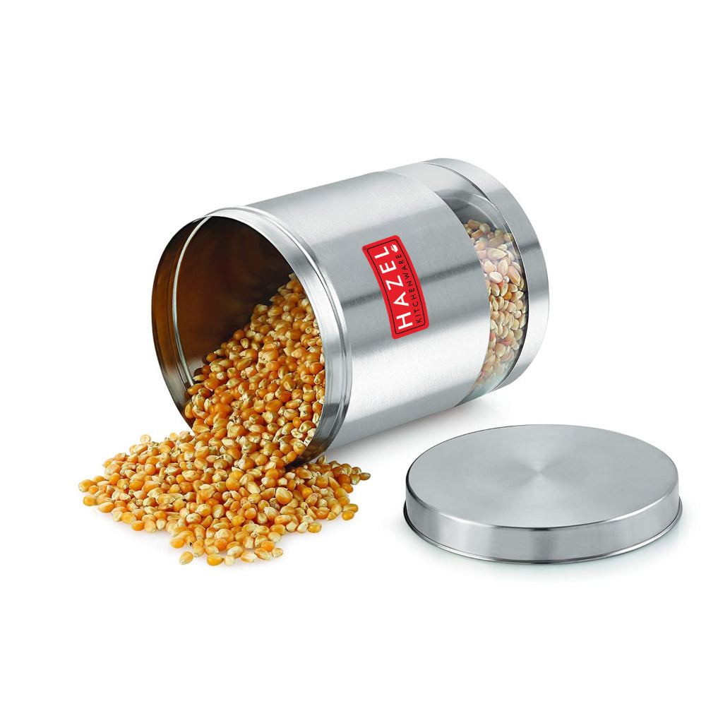 Container tipped on its side spilling corn kernels, with its lid resting separately, on a white background.