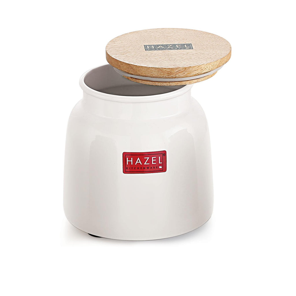White ceramic storage jar with wooden lid resting ajar on top, shown at a front angle on a plain white background.