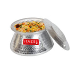 Aluminium hammered kadai filled with a biryani-style rice dish, lid separated beside it, on a white background.
