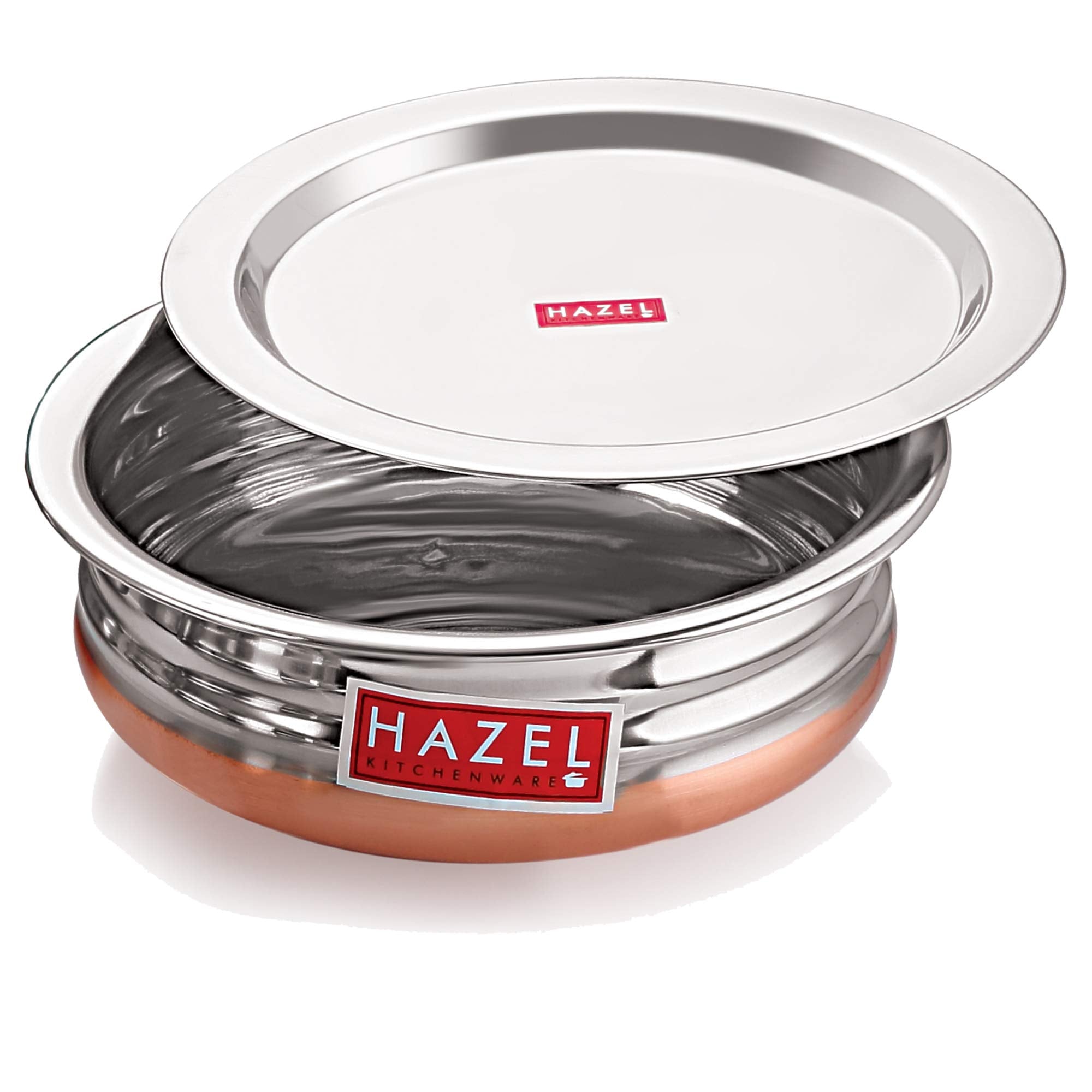 Copper-bottom urli filled with a paneer and pea curry, its lid resting tilted beside it, on a white background.