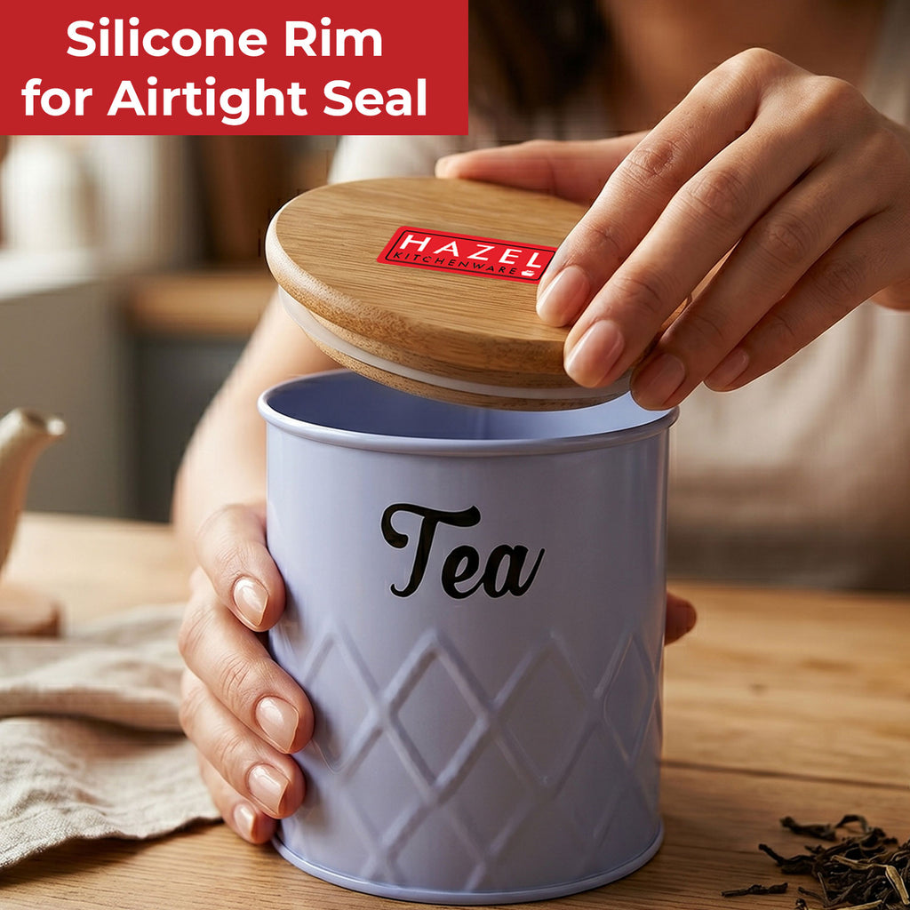 Hands lifting the wooden lid off the grey Tea canister on a wooden table with a red label reading Silicone Rim Airtight Seal.